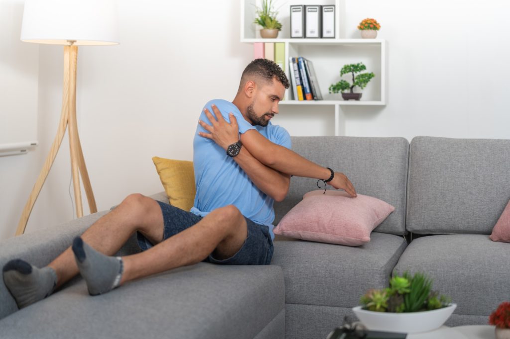 Young man with shoulder pain, doing stretching exercises